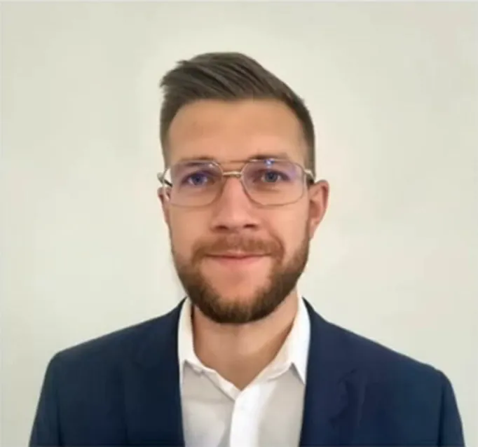 Pawel Kudosz wearing glasses, a white shirt and a dark jacket