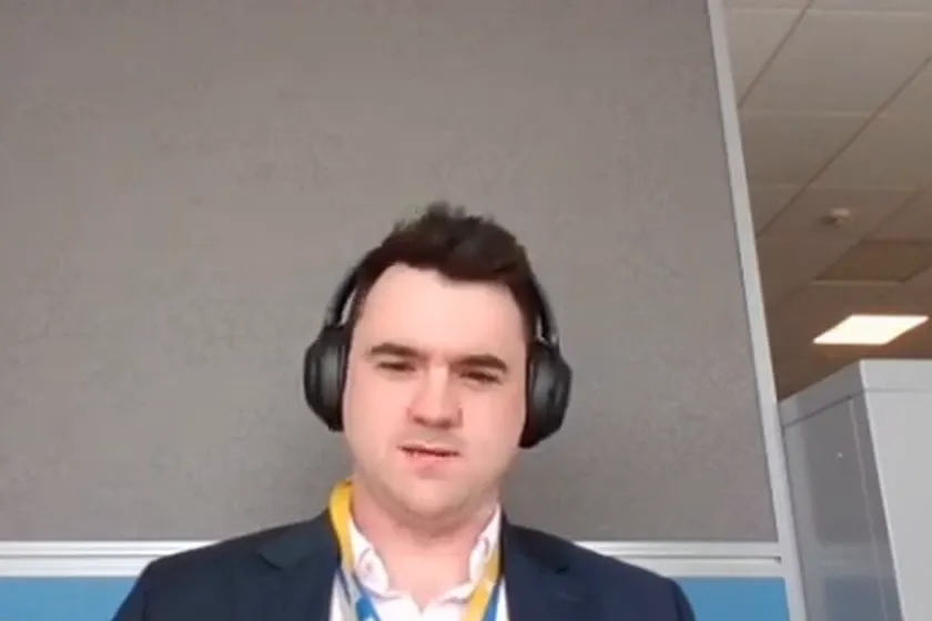 William Baker-Jones wearing headphones, a dark jacket and a yellow lanyard
