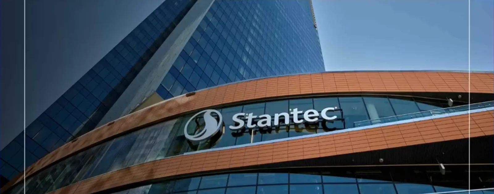 Stantec sign on a curved building facade beneath a glass tower